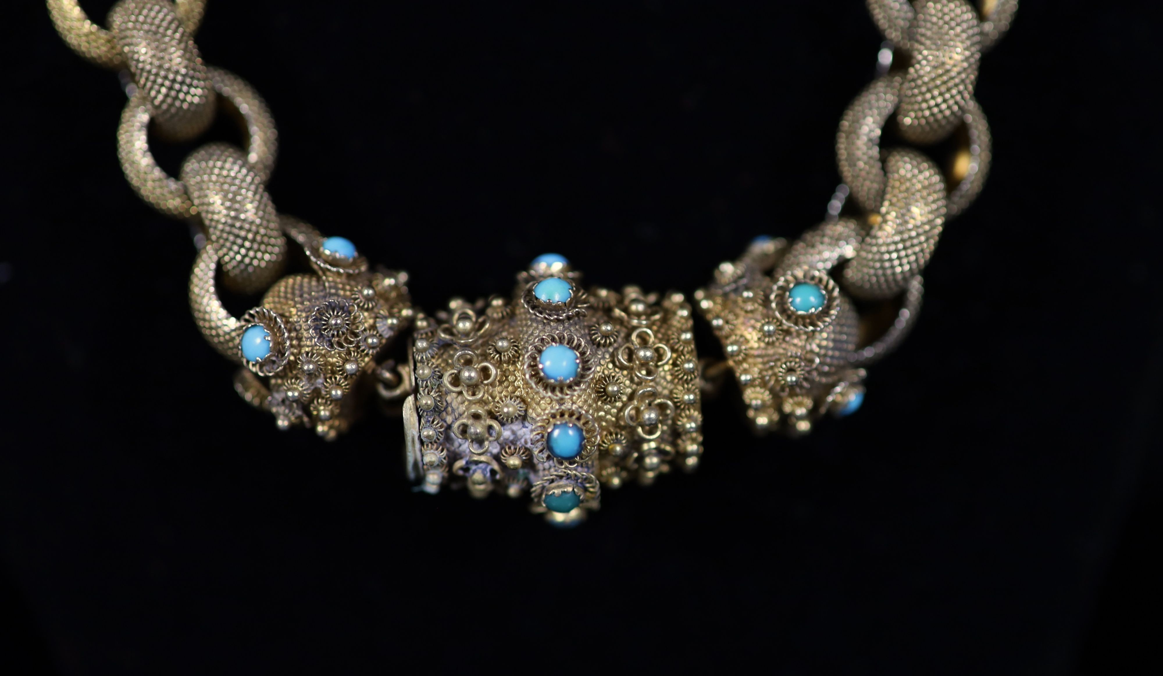 An early 19th century textured gold circular link muff chain, with turquoise set and cannetille work barrel shaped clasp